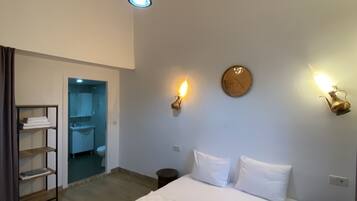 A bedroom with a large bed, a wardrobe, a bathroom, and a ceiling light.
