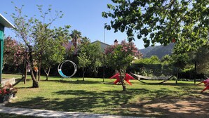 Un jardín con un columpio, una hamaca y un circuito de columpios.