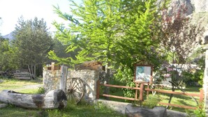 A rustic wooden gate with a sign, a stone wall, and a wooden cart. - Auberge La Cleida (Nevache)