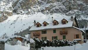 A snow-covered chalet with a balcony, set against a mountainous backdrop. - Auberge La Cleida (Nevache)