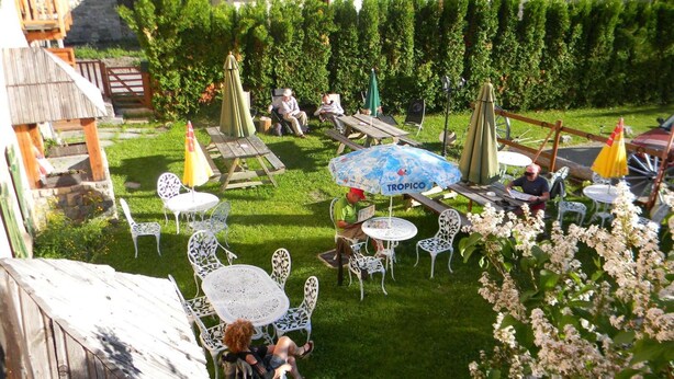 A garden patio with outdoor seating, including tables and chairs, surrounded by greenery and a wooden fence. - Auberge La Cleida (Nevache)