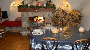 A dining area with a stone fireplace, a table set for four, and a Christmas tree decoration. - Auberge La Cleida (Nevache)