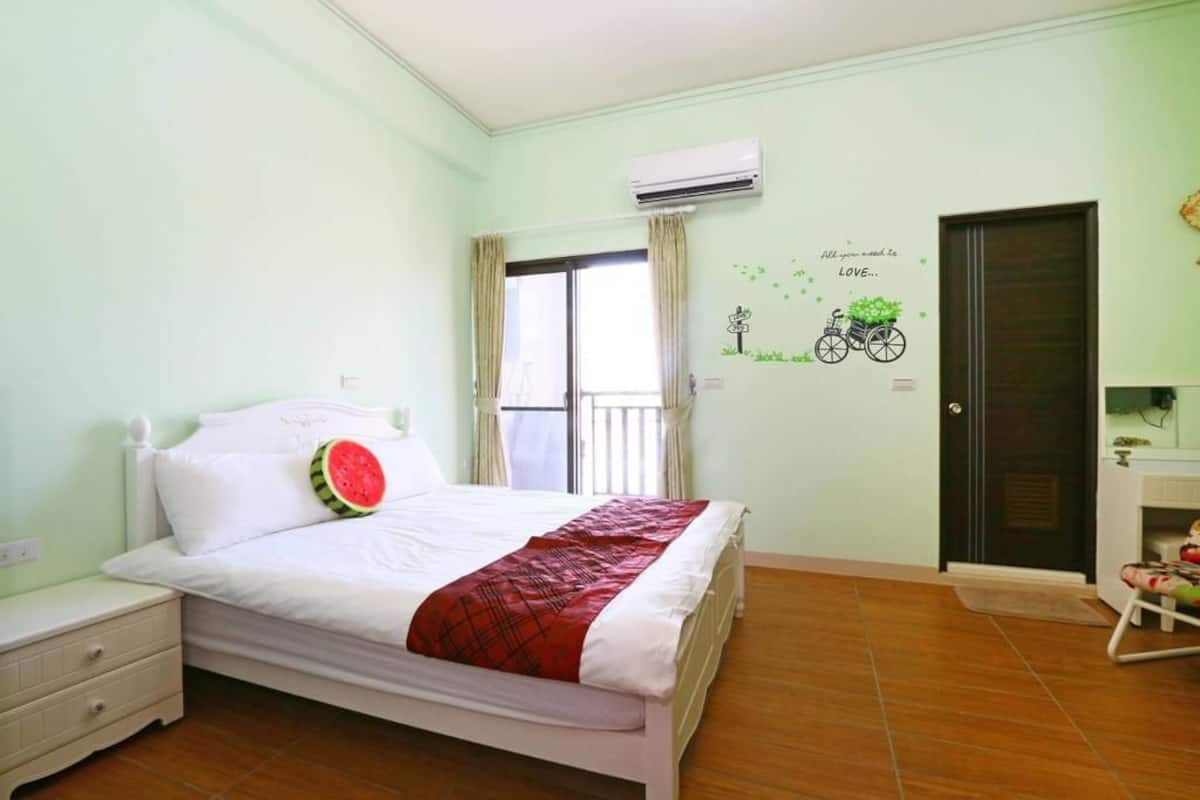 A bedroom with a bed, a nightstand, a dresser, and a door.