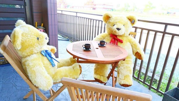 Two yellow teddy bears sitting at a round wooden table with two cups on saucers. - Birds Flower B&B (Wujie)