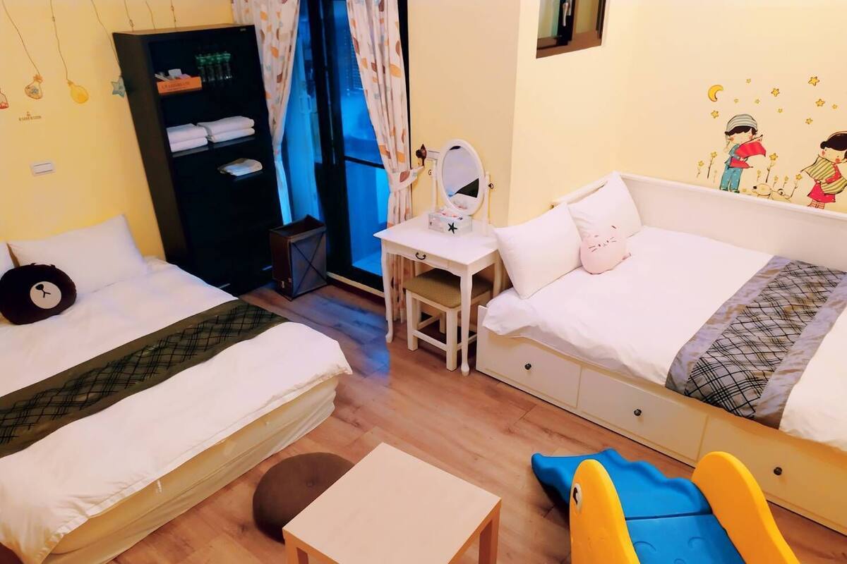 A hotel room with two beds, a desk, and a small table.