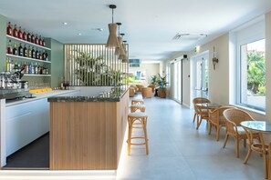 Un área de bar moderna con mostrador de madera, sillas de mimbre y vistas al exterior.