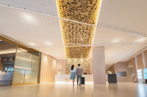 Un moderno vestíbulo de hotel con una recepción, techo con motivos y diseño limpio y minimalista.