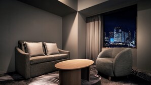 Een moderne hotelkamer met een bank, fauteuil en een rond bijzettafeltje.