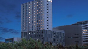 Een modern hotelgebouw met een raster van ramen en een bord waarop 'HOTEL JAL CITY' staat.