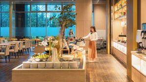 Een modern café met een buffetopstelling, houten vloeren en grote ramen.