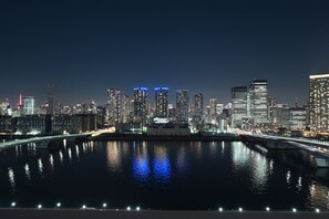 Une vue nocturne d’une ville, avec une rivière et des ponts illuminés.