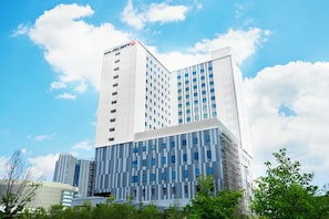 A modern hotel with a prominent 'HOTEL JALGITY' sign, featuring a mix of white and gray facades, multiple windows, and a clear sky with clouds. - Hotel JAL City Tokyo Toyosu (Tokyo)