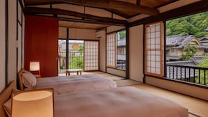 A traditional Japanese room with tatami flooring, a low wooden ceiling, and sliding doors leading to a balcony.