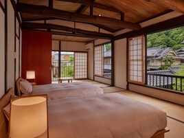 Una habitación japonesa tradicional con suelo de tatami, techo de madera bajo y puertas correderas que dan a un balcón.