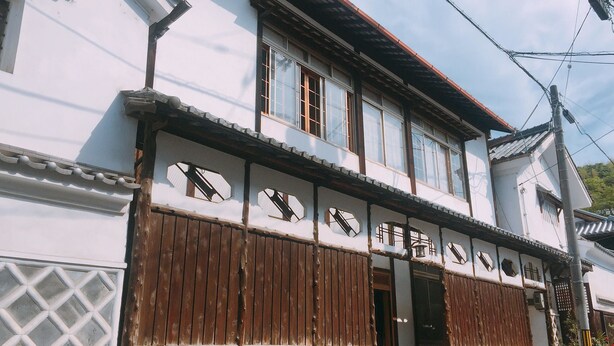 A traditional building with multiple windows, wooden shutters, and a stone foundation.