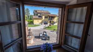 A view from a window of a house with a patio area, a stone pathway, and outdoor furniture. - Borgo Terrosi (Sinalunga)