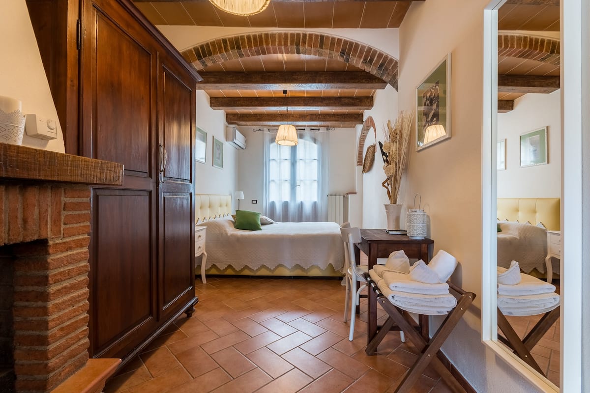 Una habitación acogedora con una cama, una silla, una mesa y un espejo.
