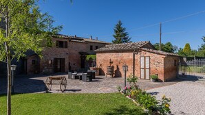 A rustic brick house with a patio, outdoor furniture, and a horse-drawn carriage. - Borgo Terrosi (Sinalunga)