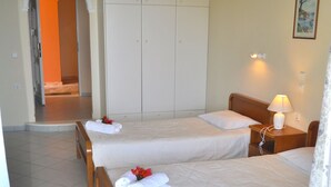 Ein Hotelzimmer mit zwei Betten, einem Kleiderschrank, einem Nachttisch mit Lampe und einem Bild an der Wand.