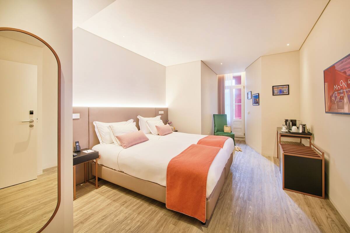 Ein modernes Hotelzimmer mit einem großen Bett, Nachttischen, einem Schreibtisch und einem Sessel.