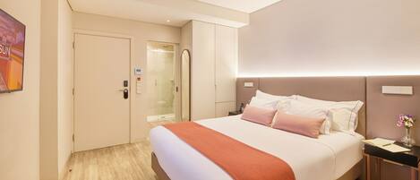 Una habitación de hotel moderna con una cama grande, una mesita de noche y un espejo.