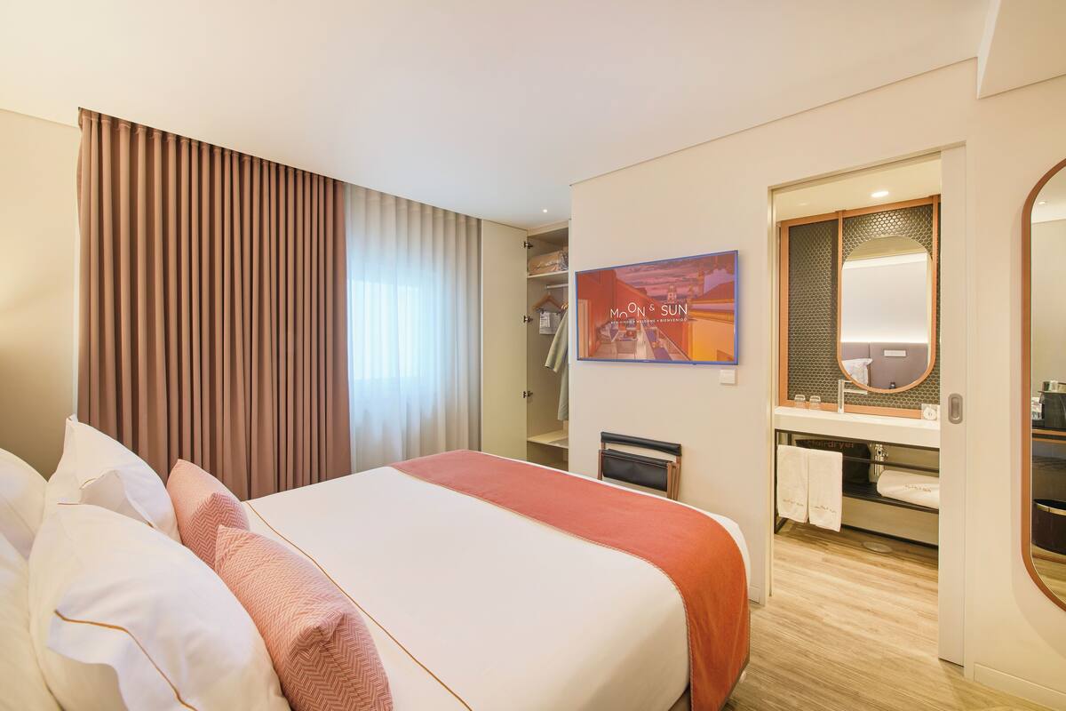 Ein Hotelzimmer mit einem großen Bett, einer Dusche, einem Schminktisch mit Spiegel und einem gerahmten Bild an der Wand.