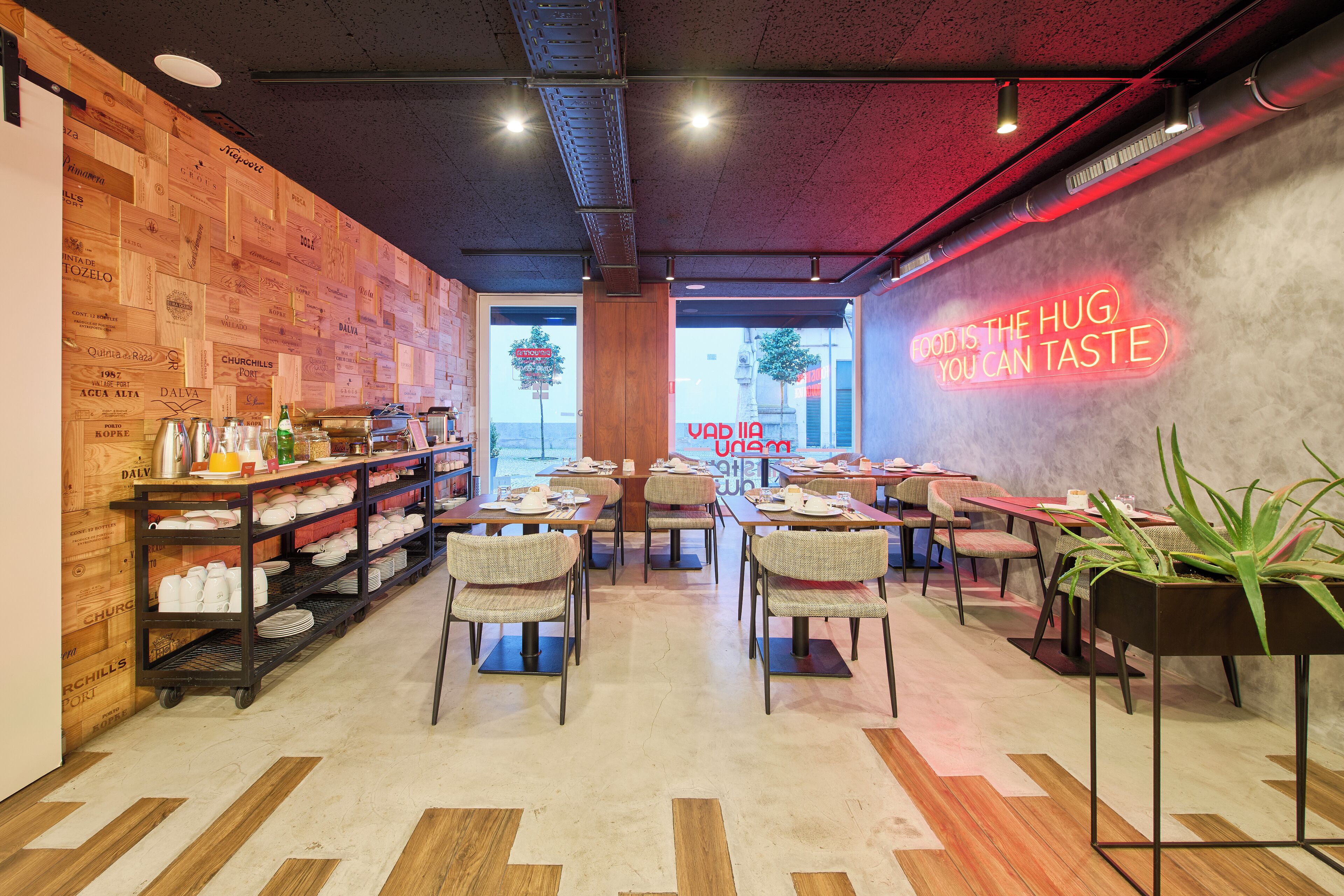 En hyggelig café med trævægge, et neonskilt der siger "HUG IS THE HUG YOU CAN TASTE", og forskellige siddepladser.