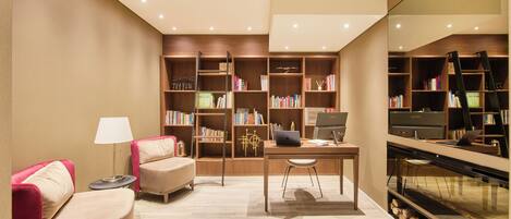 Een moderne woonkamer met een bank, een bureau met een laptop en een boekenkast vol boeken.