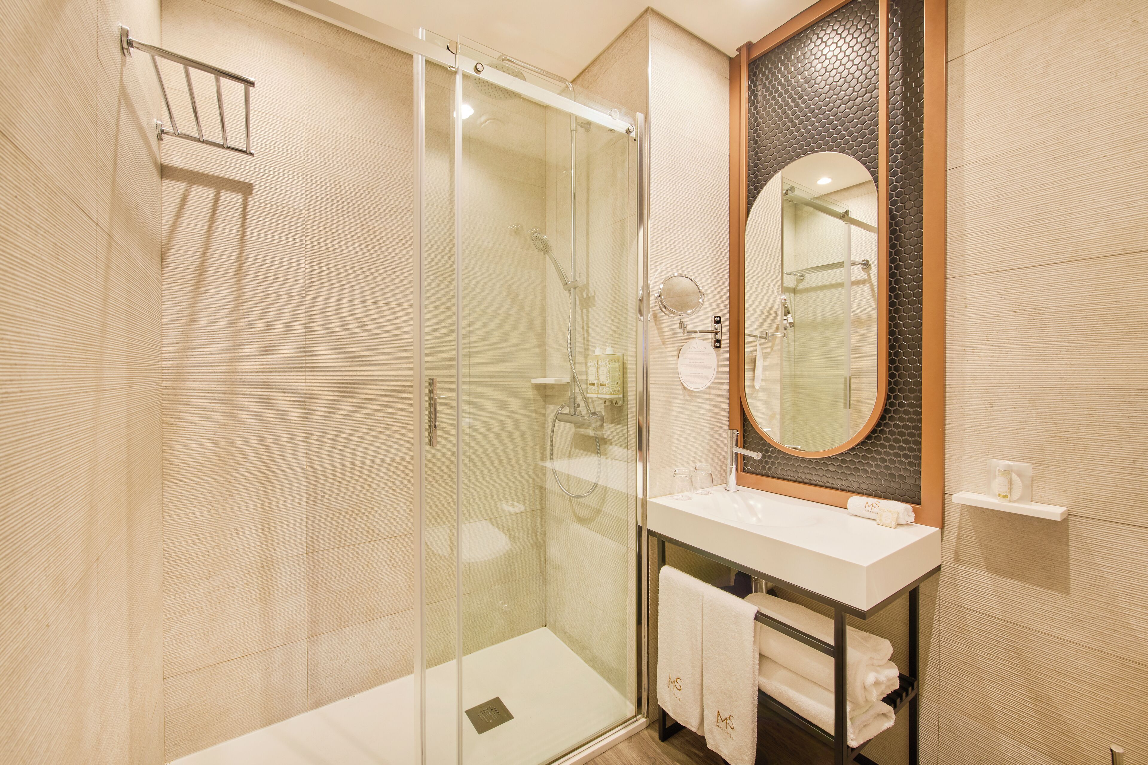 A modern bathroom with a glass-enclosed shower, a white sink, and a large mirror.