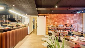 Een restaurant met een houten toonbank, tafels met stoelen en een muur met verschillende logo's.
