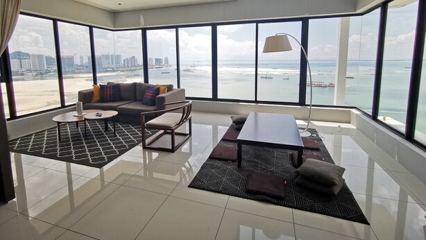 A spacious living area with a large window offering a city and beach view. - Family Suite Sunrise Gurney Penang (George Town)