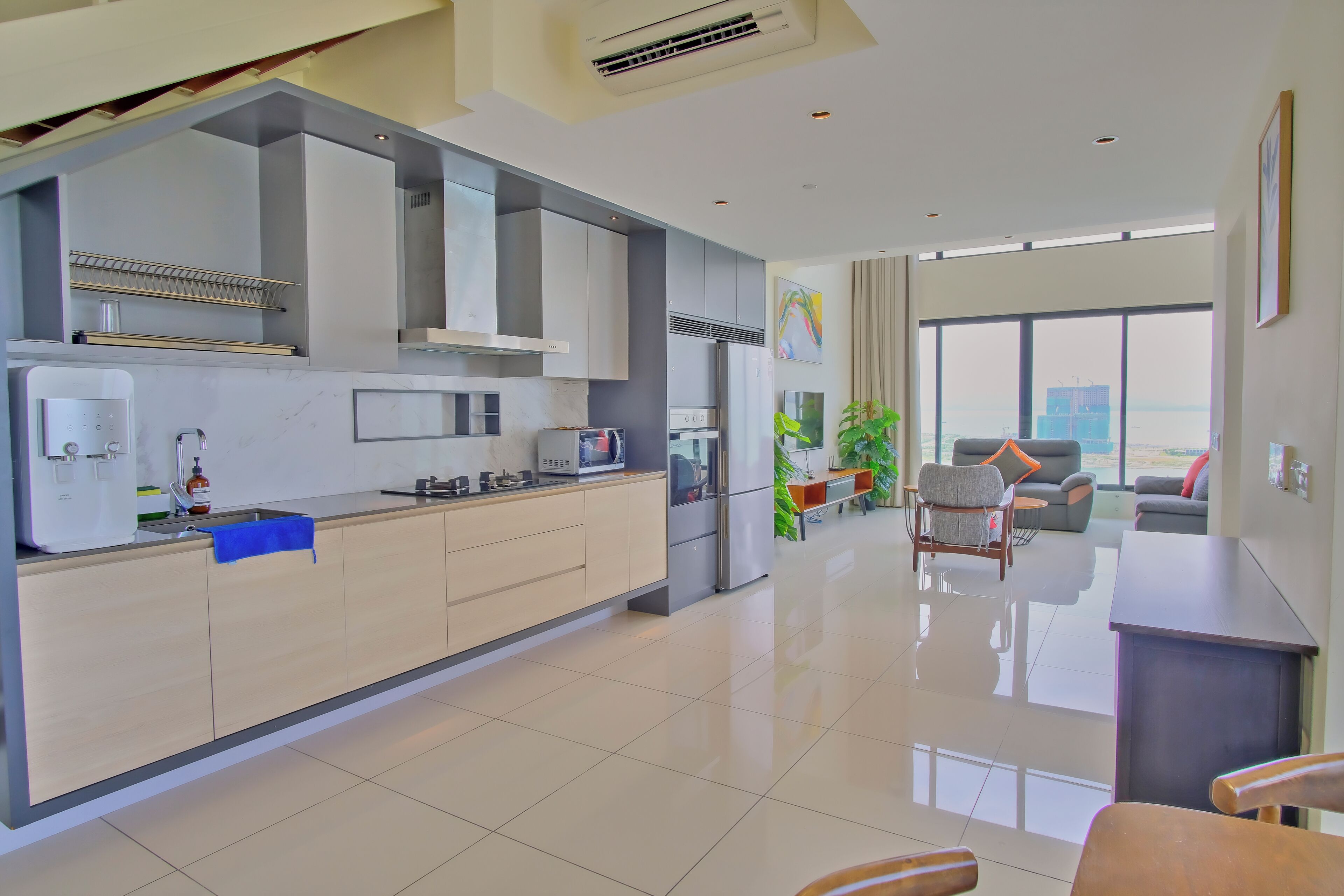 A modern kitchen with a central island, stainless steel appliances, and a dining area with a sofa and chairs.