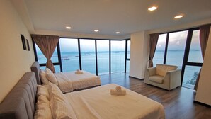 A spacious room with two beds, a sofa, and large windows offering a view of the sea. - Family Suite Sunrise Gurney Penang (George Town)