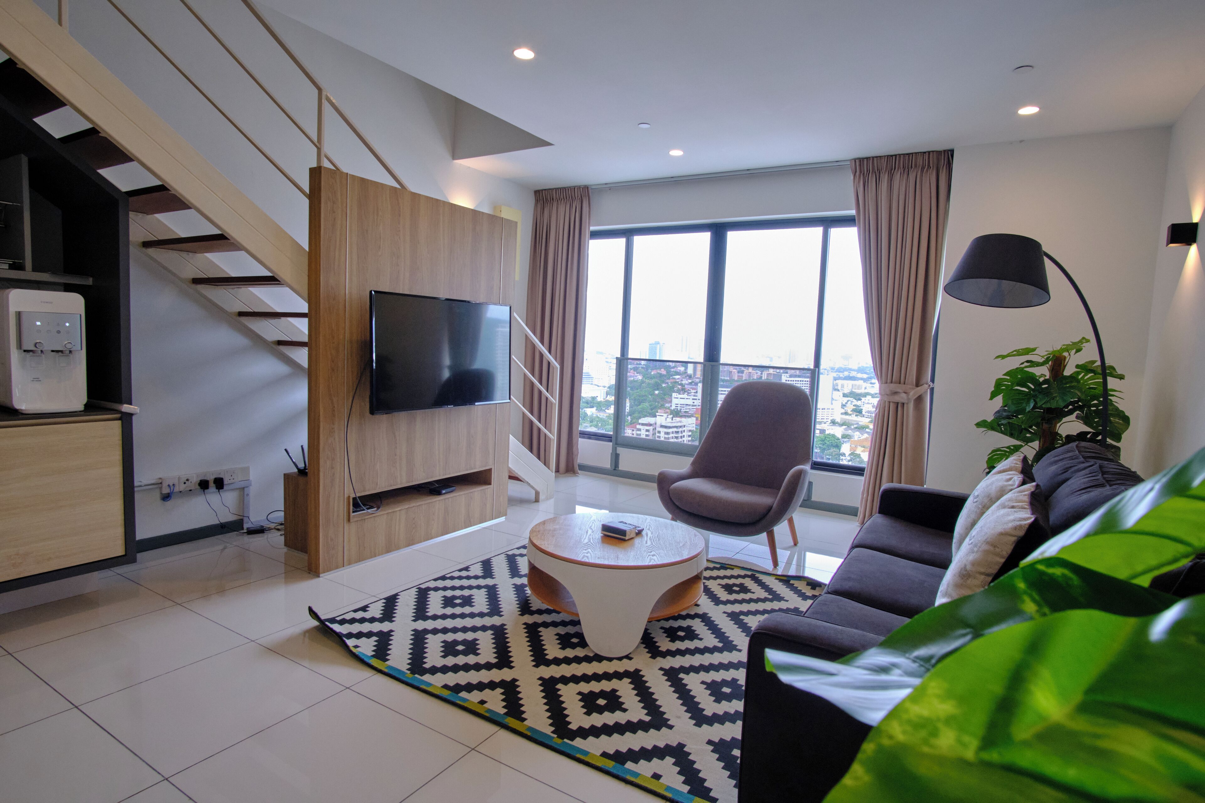 Ein modernes Wohnzimmer mit einer Couch, einem Couchtisch, einem Fernseher und einer Treppe.