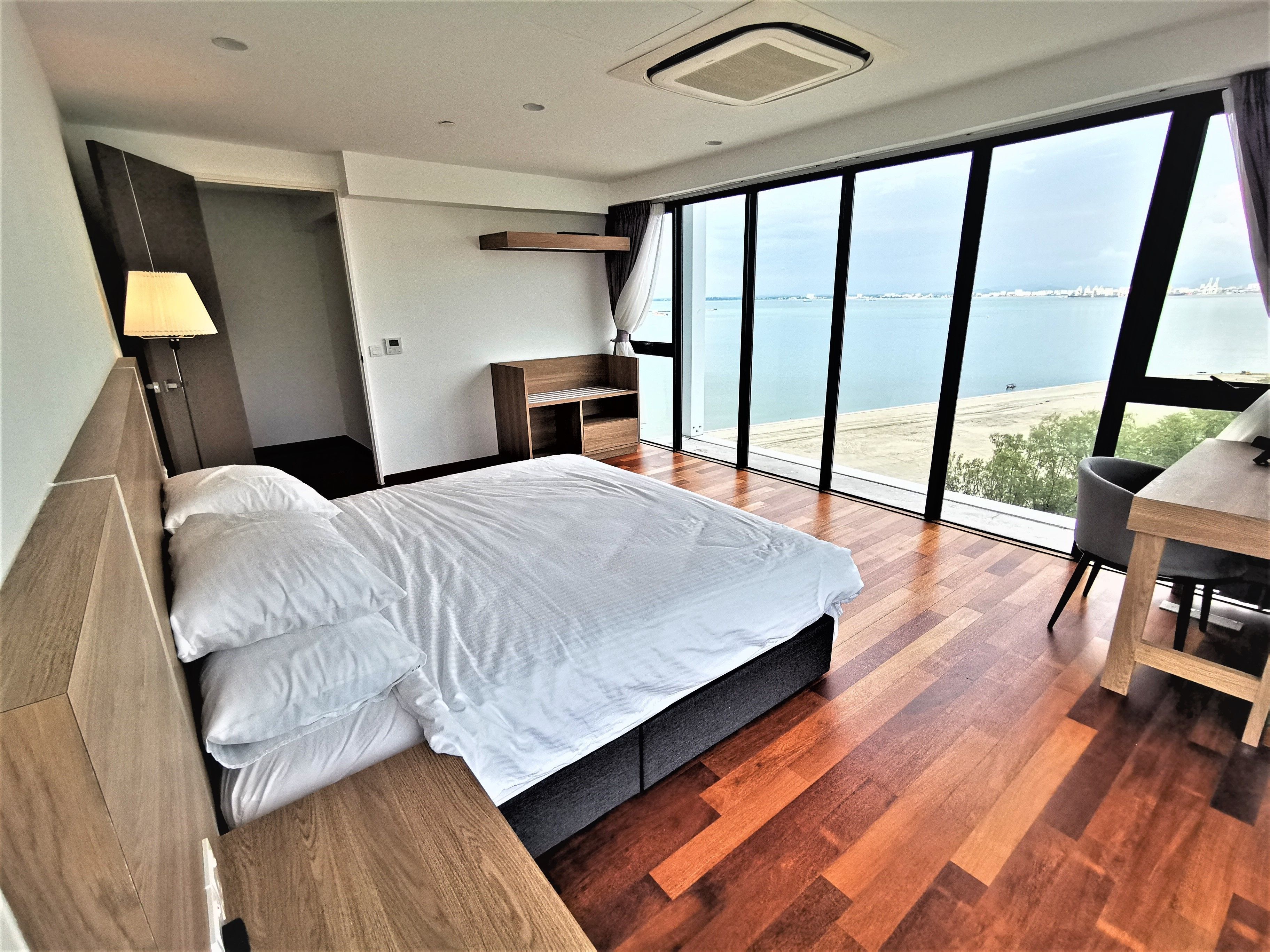Une chambre moderne avec un grand lit, un bureau et une vue sur la mer.