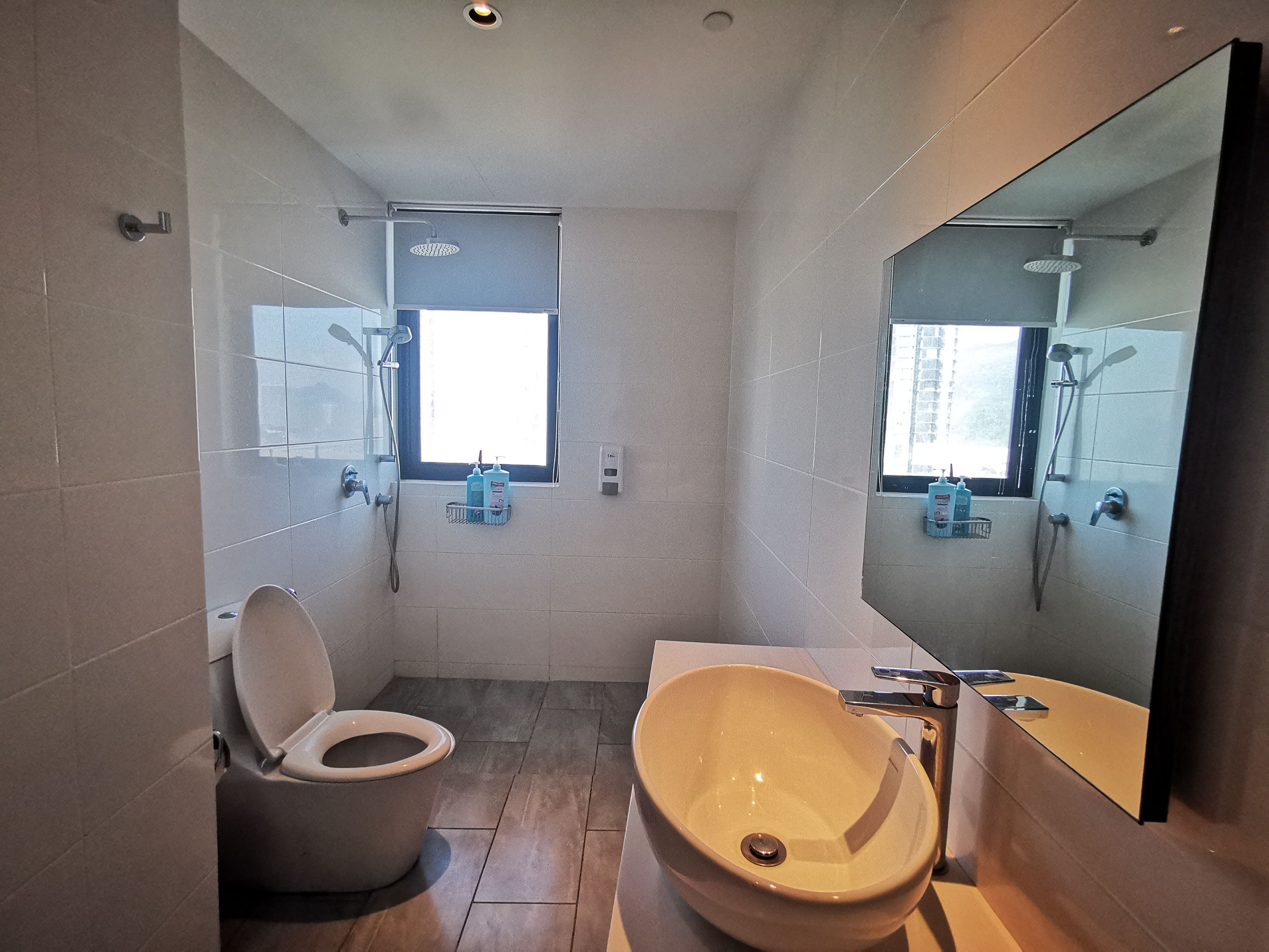 Een moderne badkamer met toilet, wastafel en douche.