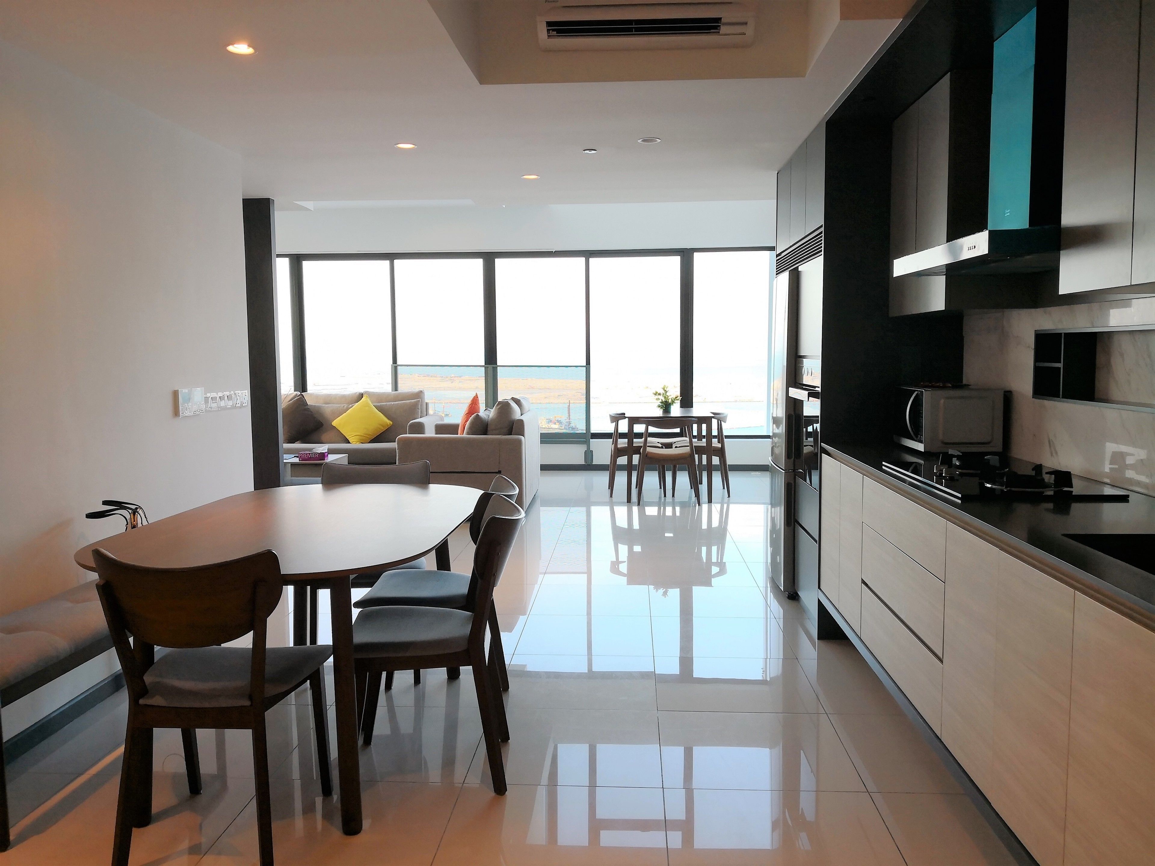 A modern kitchen with a dining area, large windows, and a view of the beach.