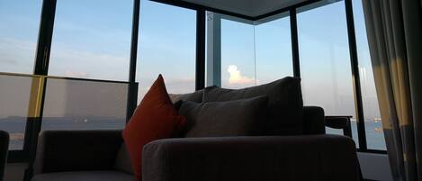 A modern room with large windows, a sofa, and a view of the sky.