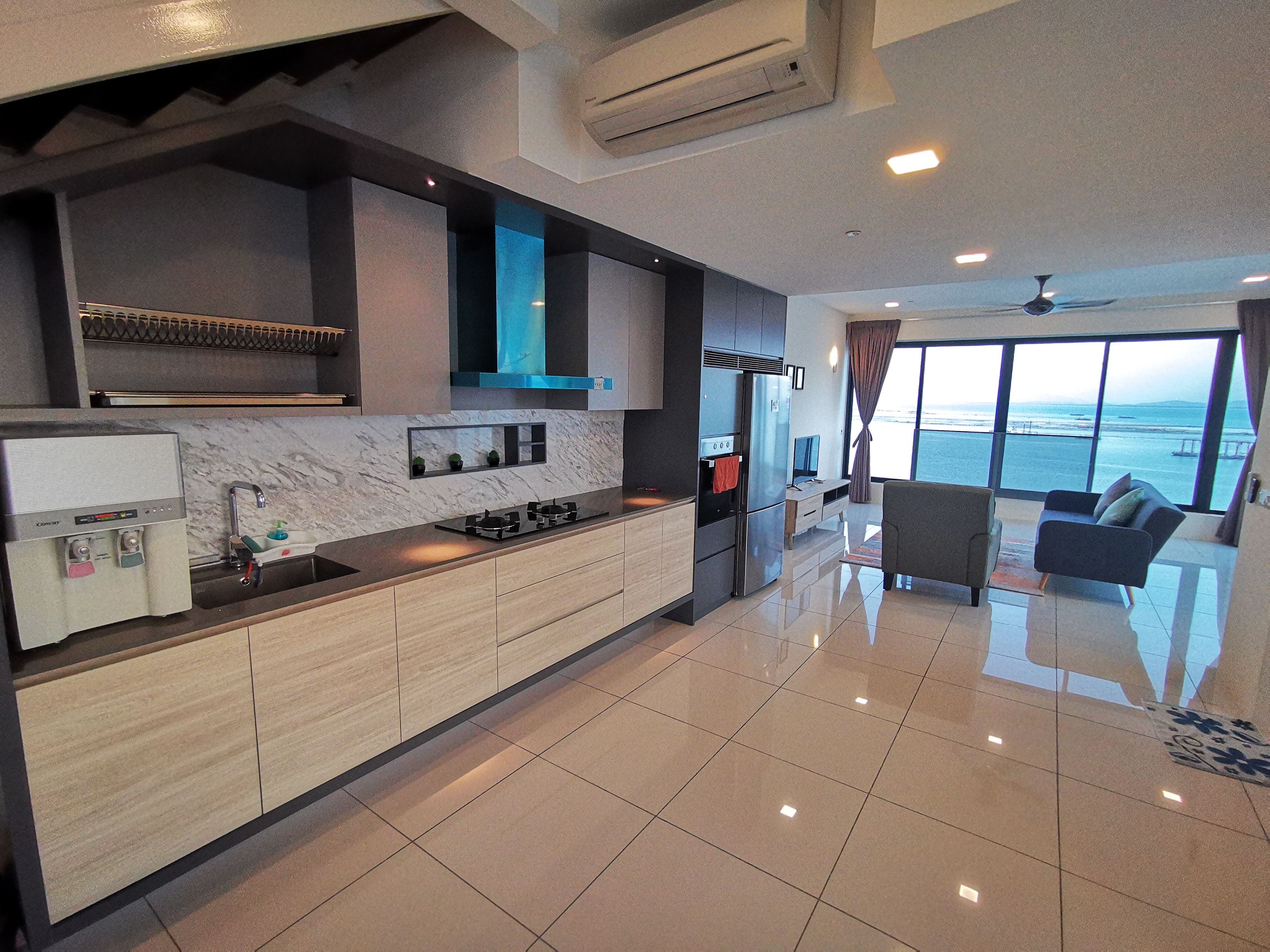 Una cucina moderna con piano cottura integrato, frigorifero e lavello. C'è una zona pranzo con un divano e vista sul mare.