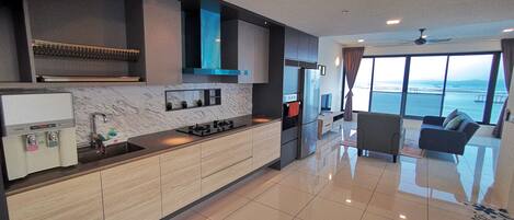 Una cucina moderna con piano cottura integrato, frigorifero e lavello. C'è una zona pranzo con un divano e vista sul mare.