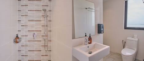 Un baño moderno con ducha, lavabo, inodoro y un espejo grande.
