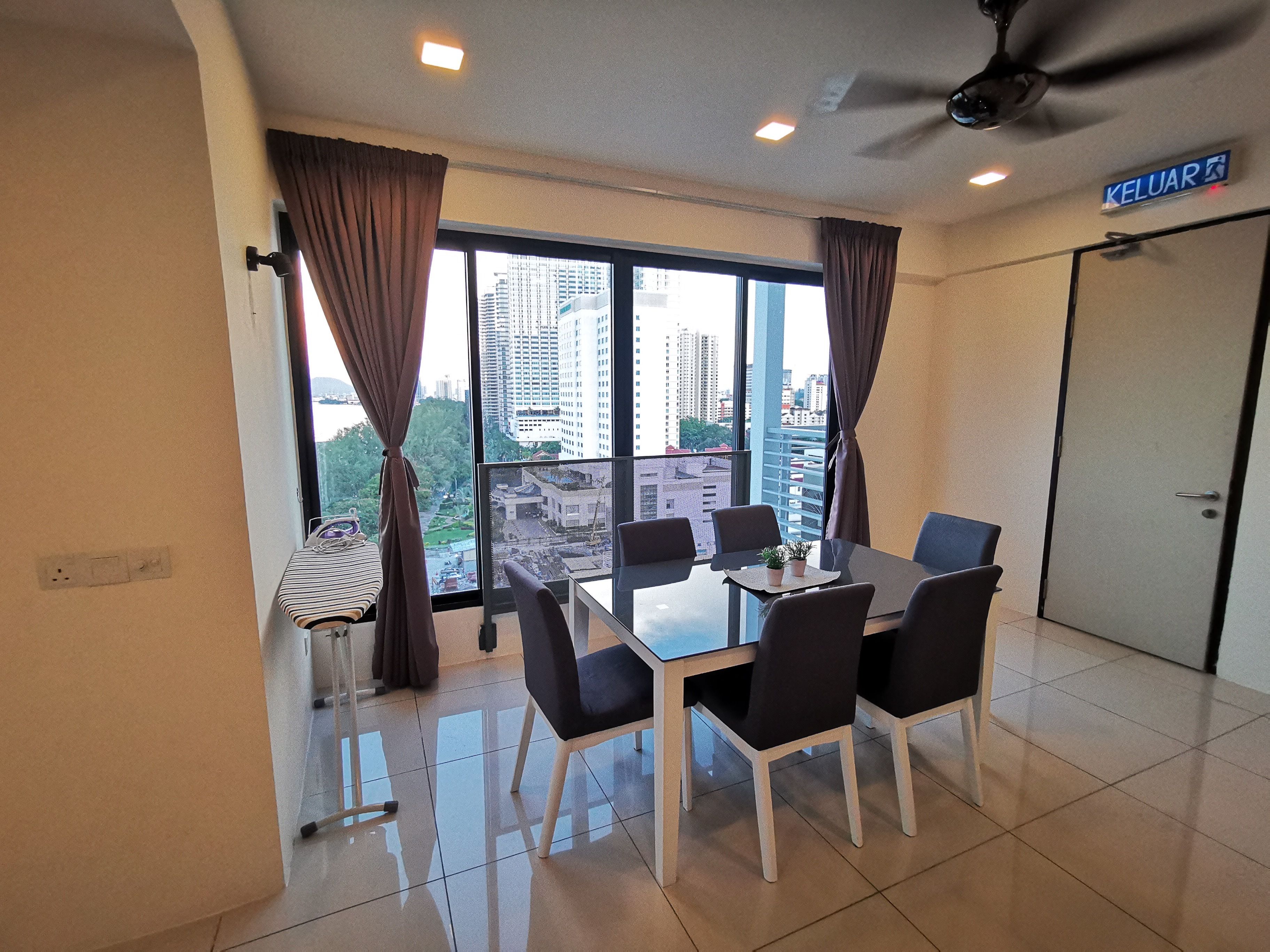 Una habitación moderna con una mesa de comedor, sillas, un ventilador de techo y un ventanal con cortinas.