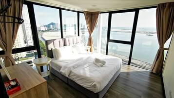 A modern hotel room with a large bed, a wooden desk, and a view of the city and water.