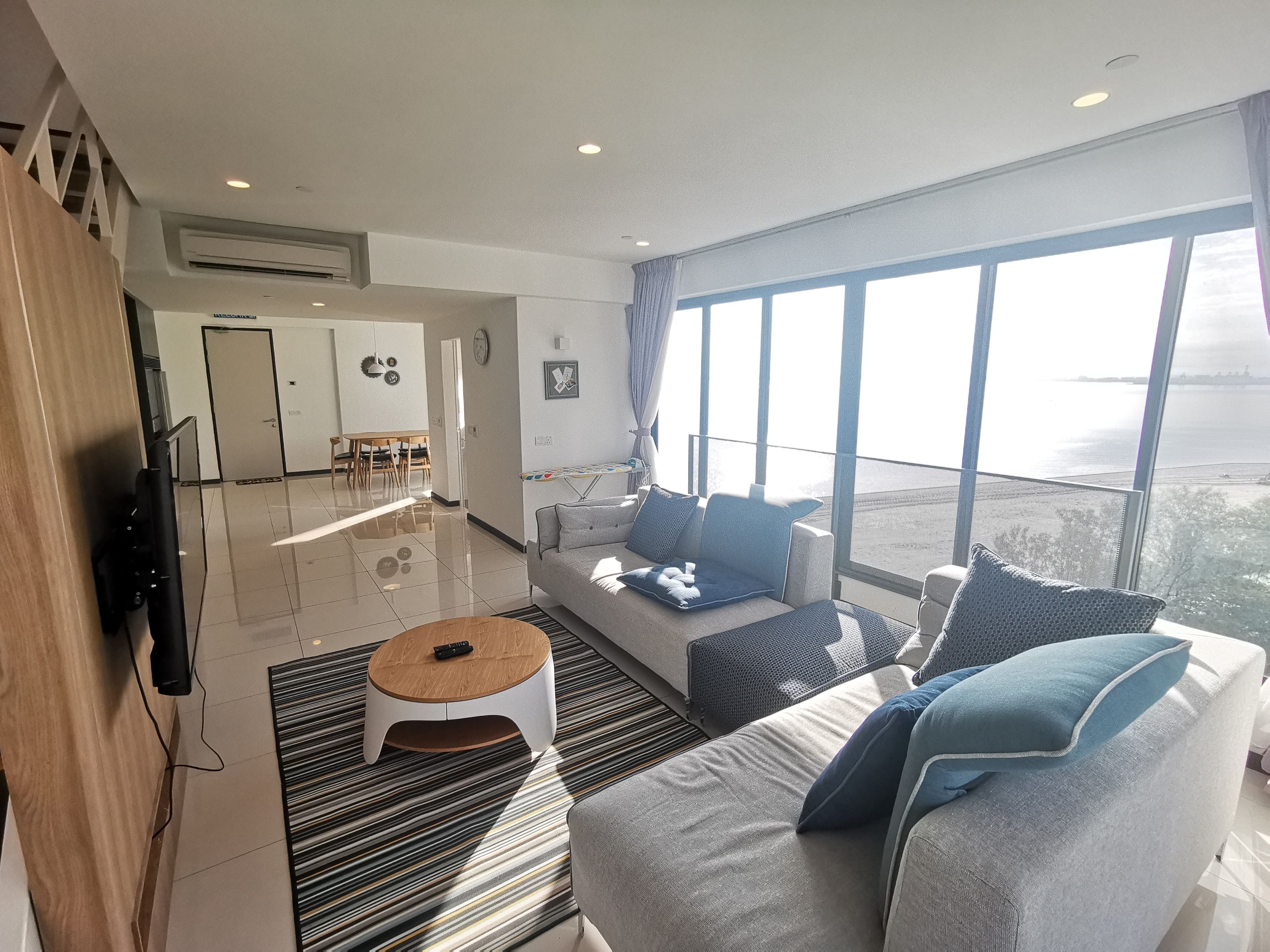 Un salon moderne avec un canapé, une table basse et de grandes fenêtres donnant sur la mer.