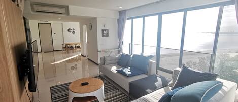 Un salon moderne avec un canapé, une table basse et de grandes fenêtres donnant sur la mer.