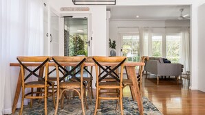Uma área de refeições com mesa e cadeiras de madeira, um sofá e vista para o exterior.