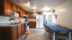 A kitchen with wooden cabinets, a microwave, a refrigerator, and a dining table with chairs. - Rainbow River Getaway (Dunnellon)