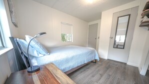A bedroom with a bed, a desk, a lamp, a window, and a mirror. - Rainbow River Getaway (Dunnellon)