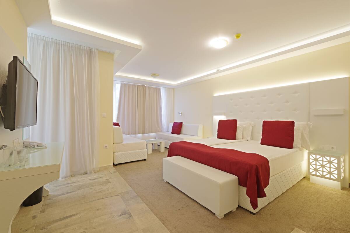 Una habitación de hotel moderna con una cama grande, un sofá, una mesita y un televisor.