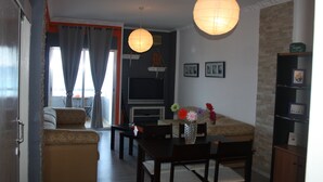 A living room with a sofa, a coffee table, a TV, and a bookshelf. - Panoramic Blue (Limassol)